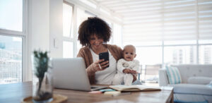 Mother holding baby and booking an appointment on her cellphone
